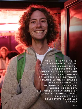 Portrait of an XD community member smiling with curly hair in warm red light, with a personal quote
